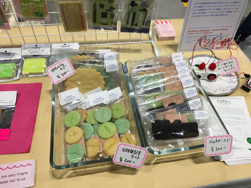 Maker Faireの物販、電子回路基板やMake:ロゴを模したクッキーを値札付きで並べた展示